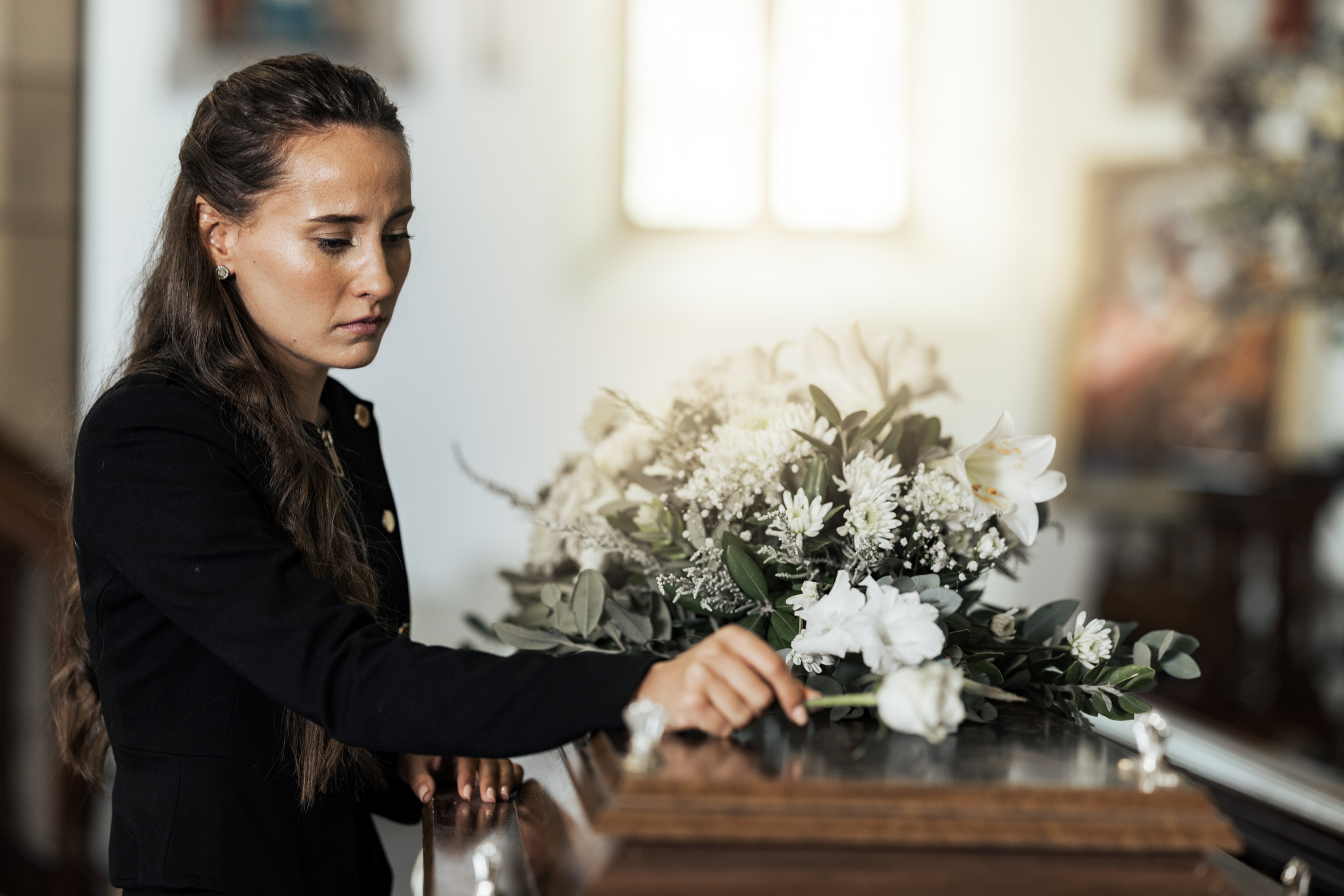 Funeral, sad and woman with flower on coffin after loss of a loved one, family or friend. Grief, death and young female putting a rose on casket in church with sadness, depression and mourning. Call our Orlando wrongful death lawyer today.