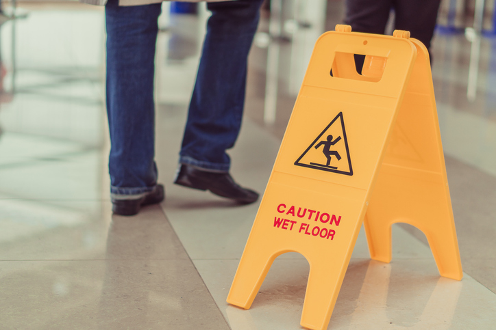 person walking around a wet floor sign - How is liability proven in a slip and fall case?